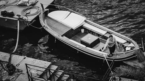 Grayscale Photo of Man in a Boat on a River