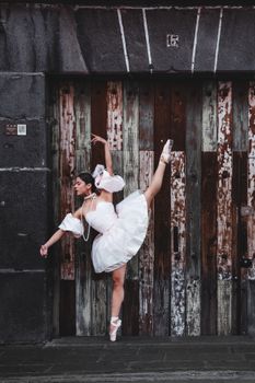 Elegant ballet dancer posing gracefully against rustic wooden doors in Puebla, Mexico.