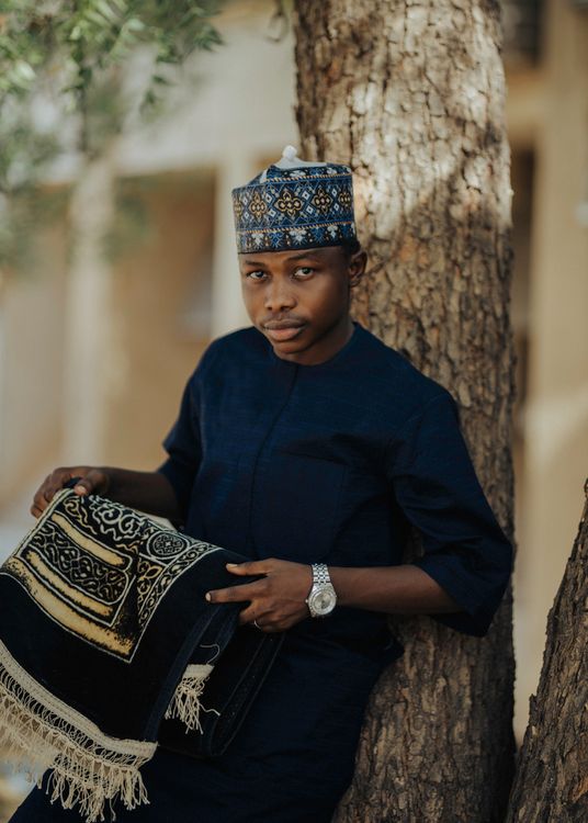 Man in Traditional African Attire Holding Prayer Mat · Free Stock Photo