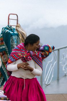 A Peruvian mother carries her child with a colorful textile wrap in Ollantaytambo, Peru.