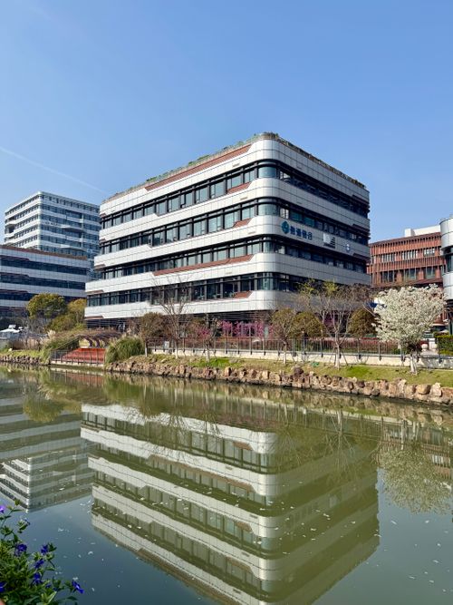 Free Contemporary office building with glass facade reflecting in a pond on a sunny day. Stock Photo