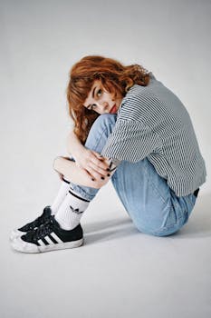 一位红发女人穿着休闲牛仔裤和条纹衫，在室内自信地摆出风格