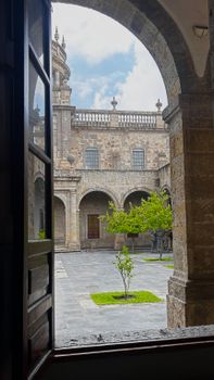View of a historic stone courtyard with arches and greenery in Guadalajara.