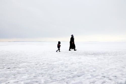 Dua Orang Berjalan Di Tanah Yang Tertutup Salju