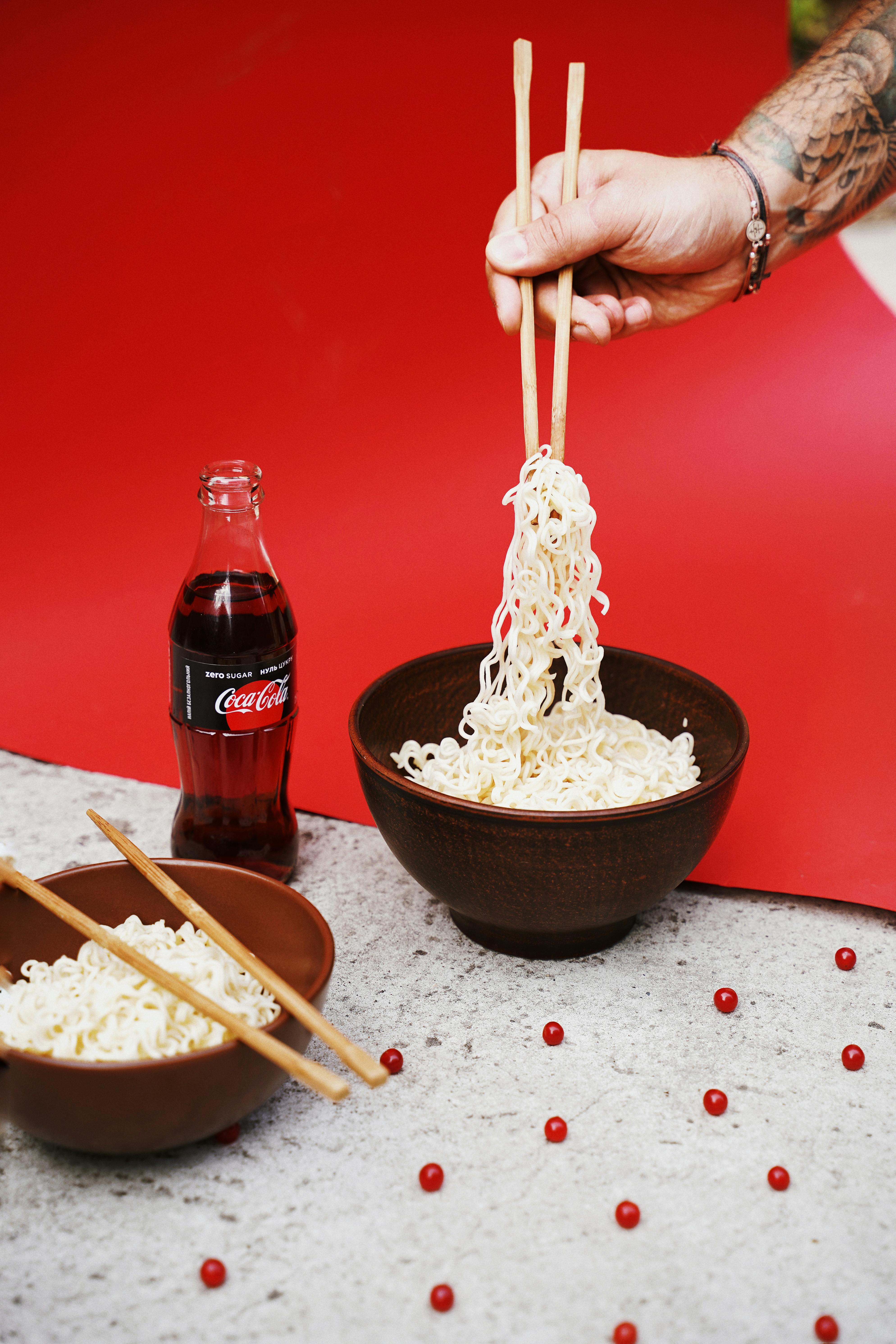Person Lifting Noodles from Ceramic Bowl With Wooden Chopsticks · Free