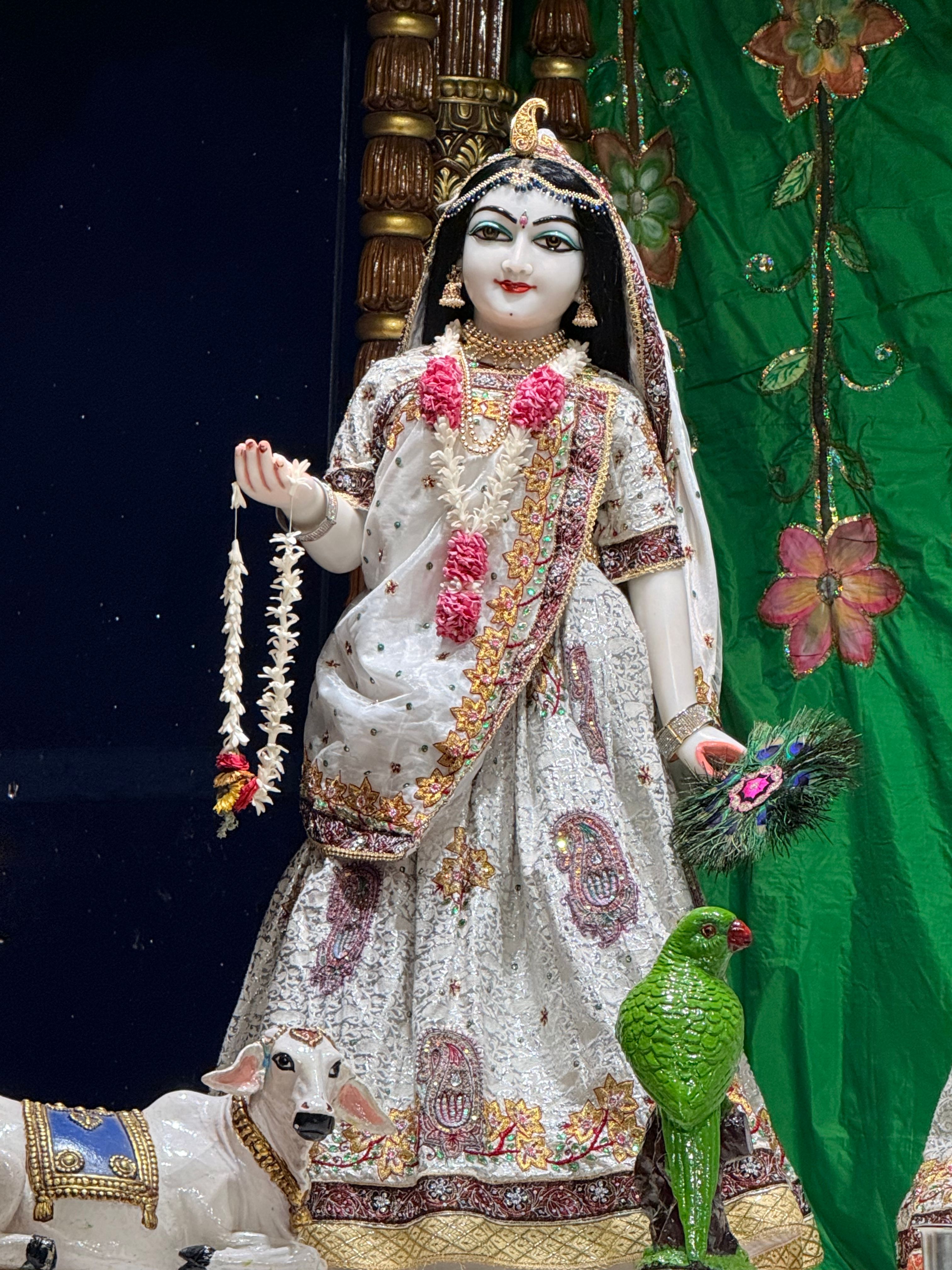Exquisite statue of a Hindu goddess adorned with floral garlands and accompanied by a cow and parrot.