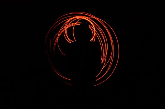 A captivating silhouette surrounded by vivid spiraling light trails against a dark background.