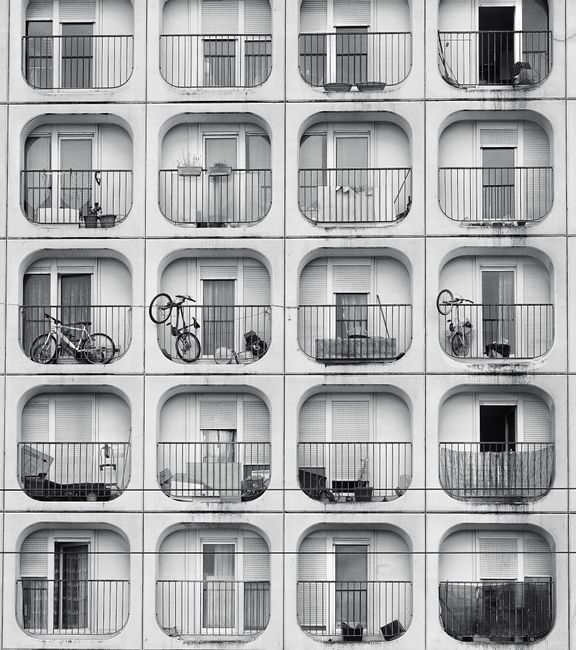 Black and white photo of apartment balconies in Bordeaux, highlighting symmetry and bicycles.