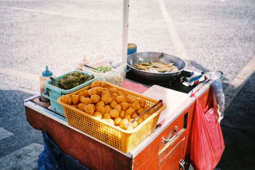 Free A vibrant Filipino street food cart displaying local delicacies like fish balls and fried snacks. Stock Photo