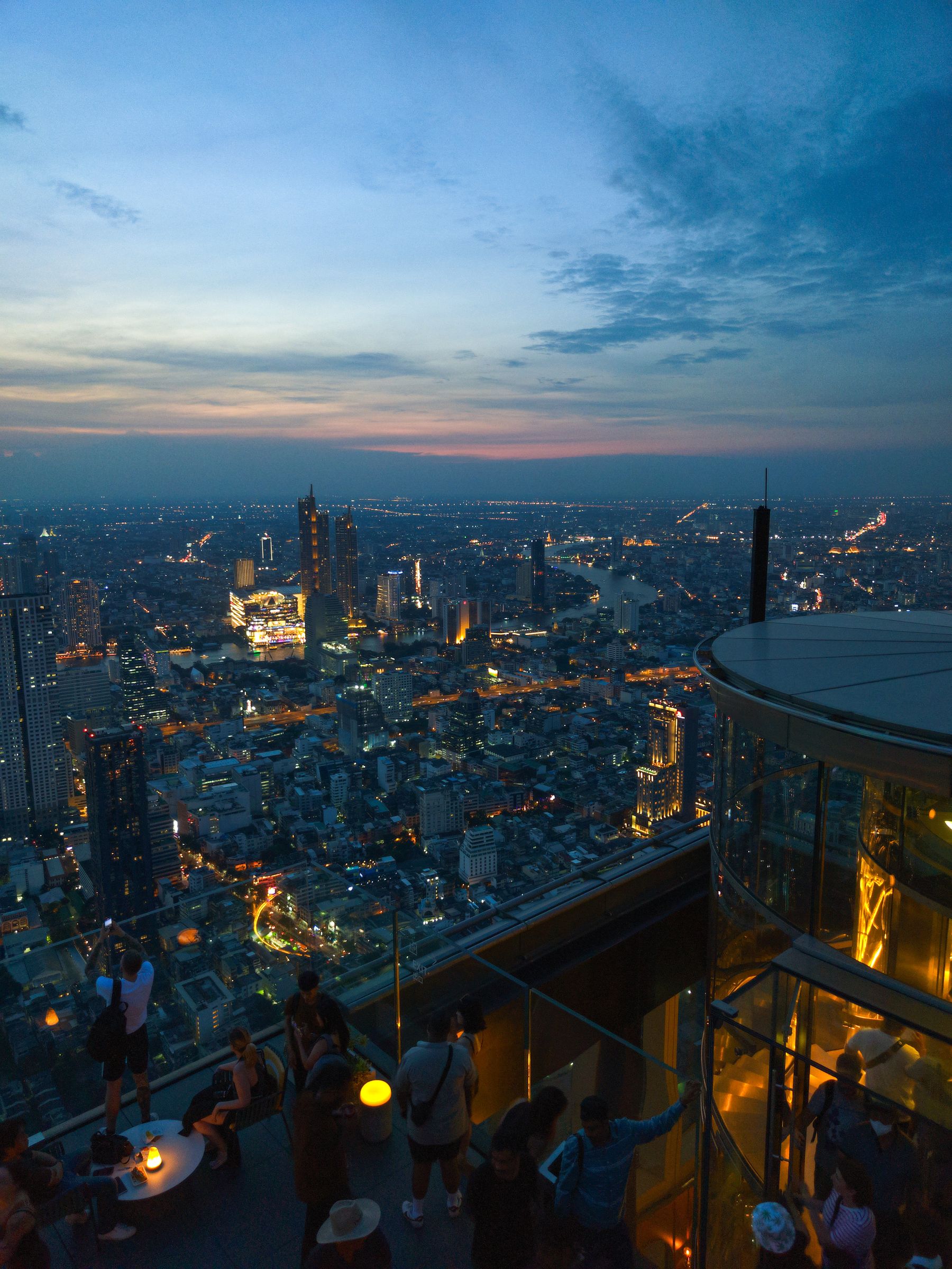 Guests enjoying a blue-hour rooftop experience above Bangkok and the Chao Phraya River