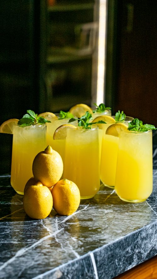 Free Refreshing lemonade glasses with lemon and mint on marble surface. Stock Photo