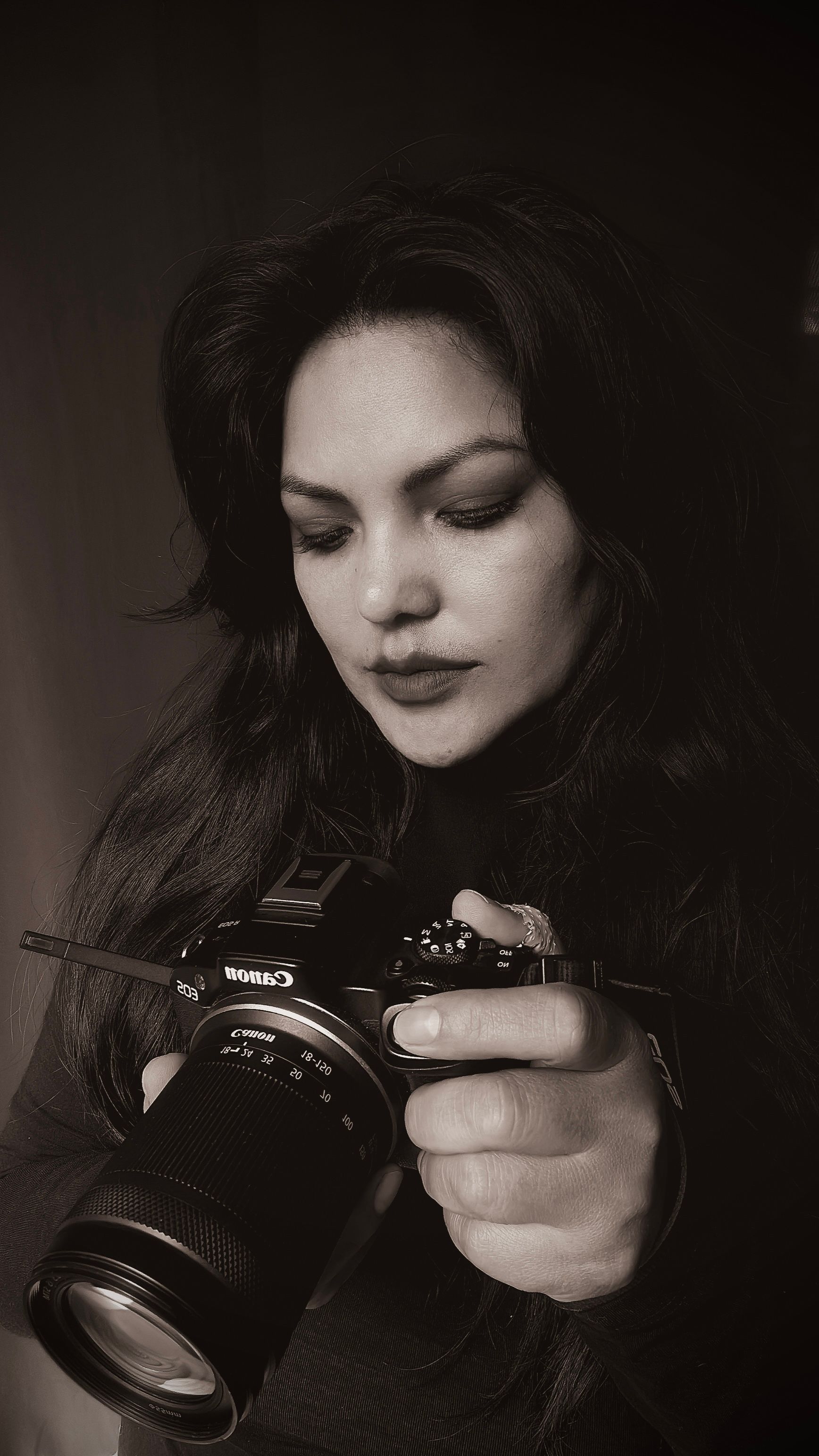 Artistic portrait of a photographer concentrating on her camera in black and white.