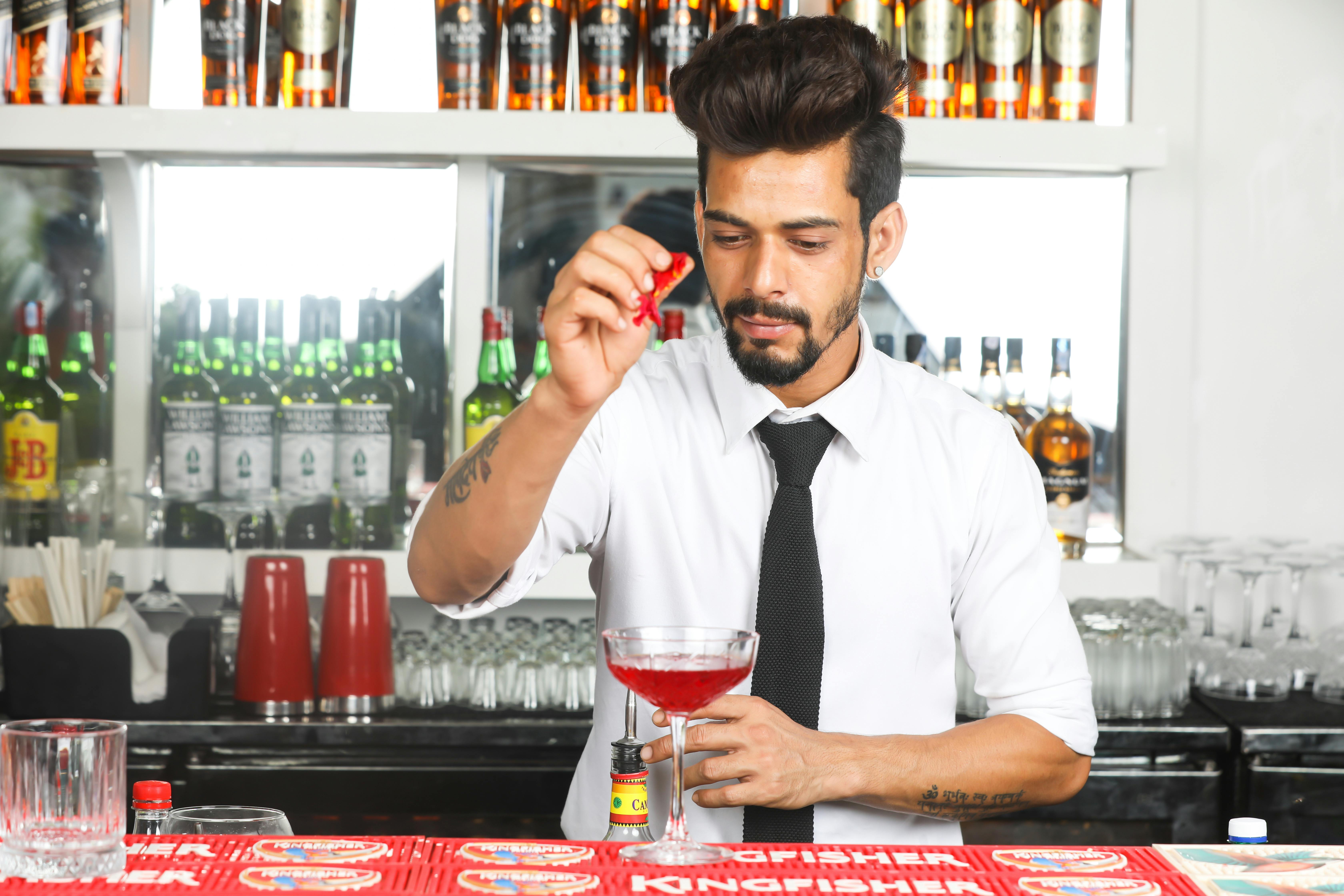 Professional bartender adding a cherry garnish to a cocktail at the bar.