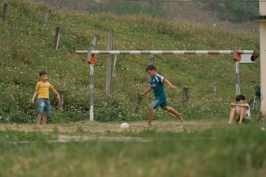Children enjoying a game of soccer in a green rural field setting.