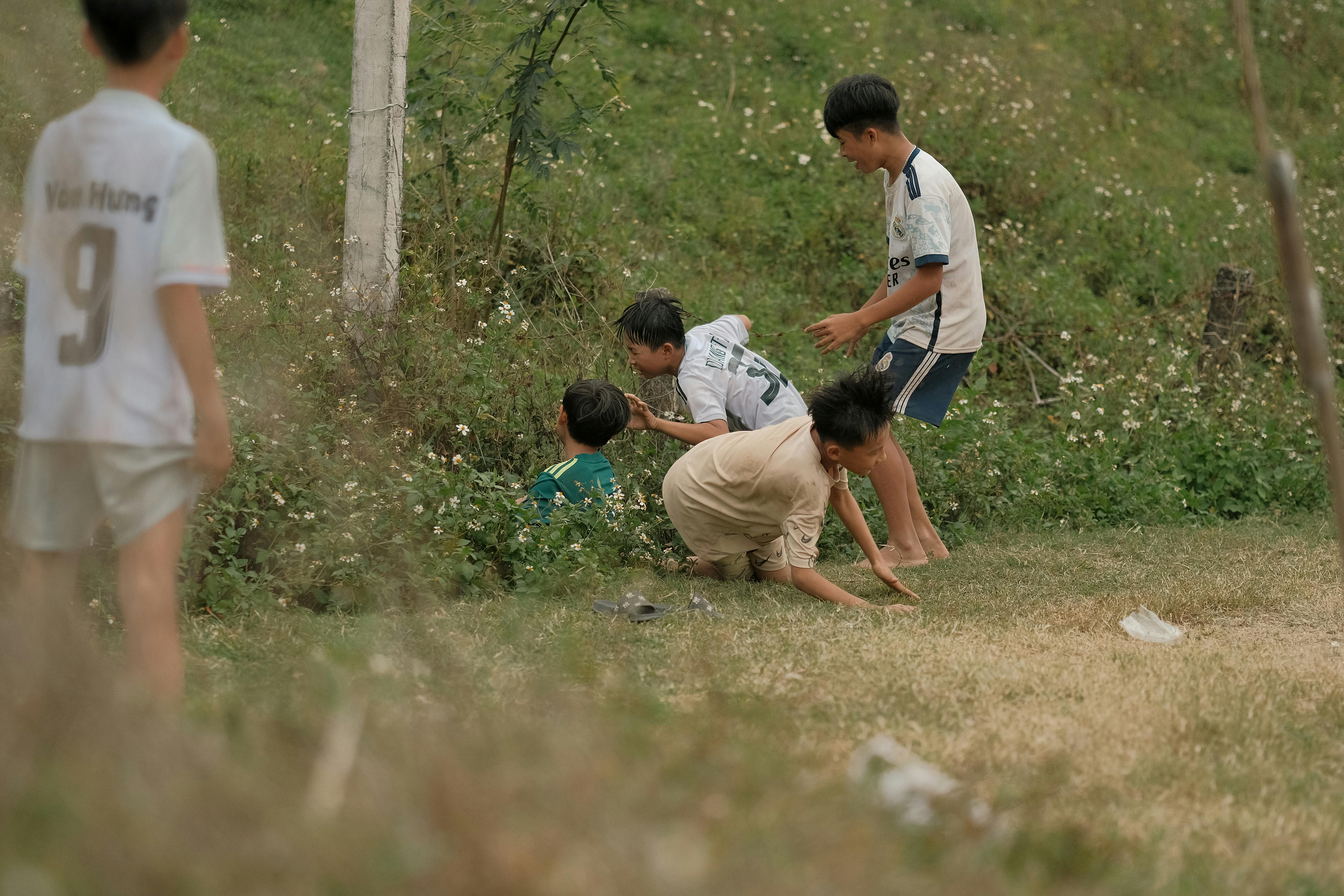 A diverse group of children and adults playing volleyball on a grassy field in Ho, with joyful expressions