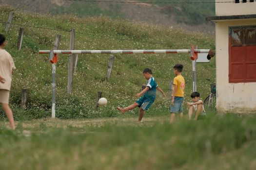 Boys enjoying a casual soccer game outdoors in a rural setting.