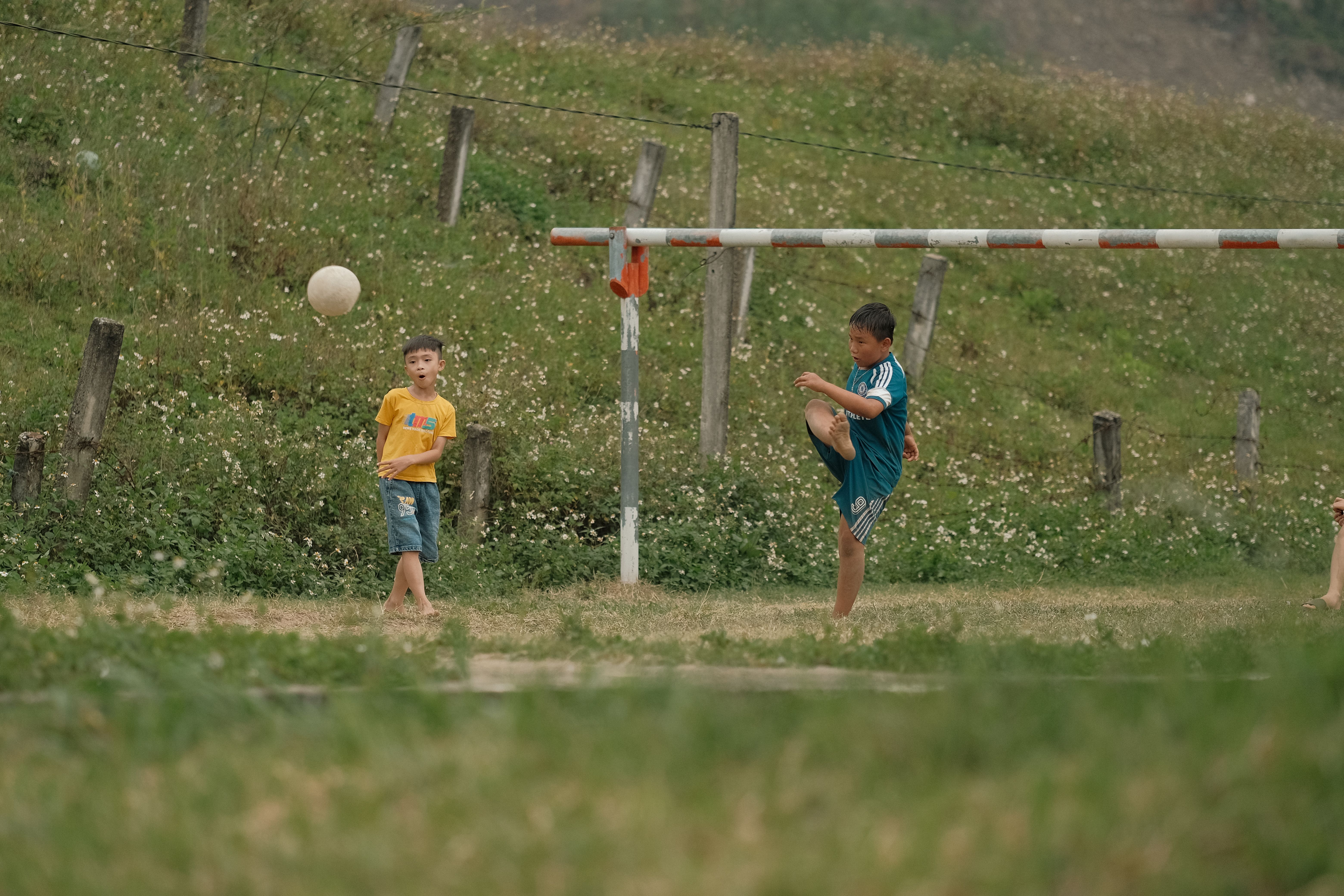 Two children enjoy a soccer game in a grassy outdoor field.