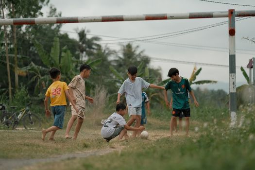 Group of children playing soccer outdoors in a rural setting