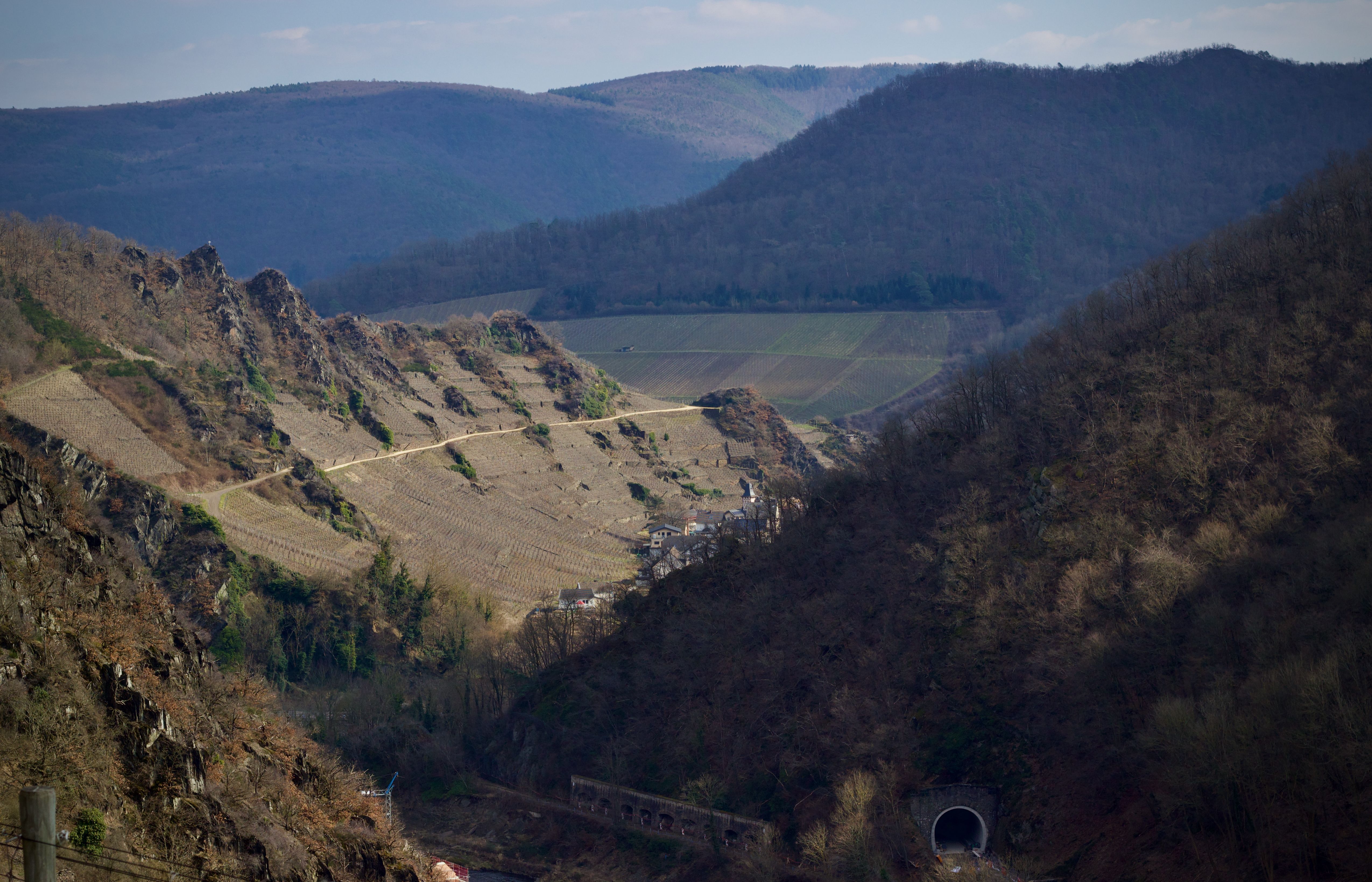 A picturesque winter landscape of hills and farmland with a visible tunnel entrance.