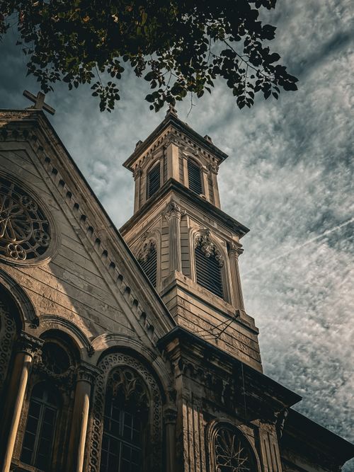 Free View of a historic church facade with intricate details and a bell tower under a dramatic sky in Istanbul. Stock Photo