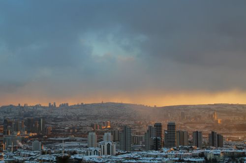 Free Stunning panoramic view of a city skyline dusted in snow, under a dramatic sunset sky. Stock Photo