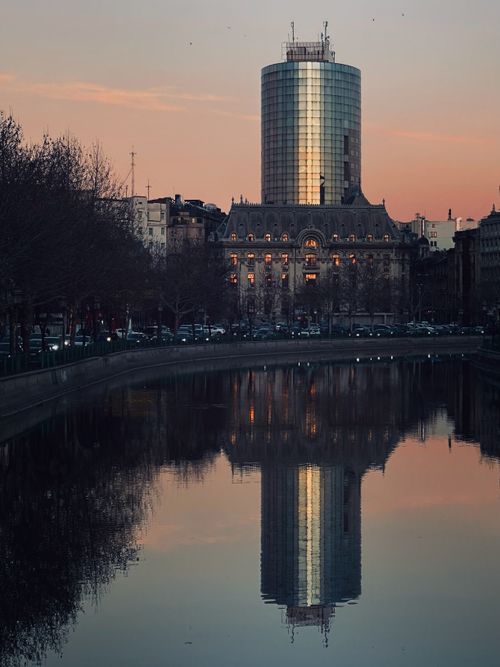 Free Stunning Bucharest cityscape at sunset with building reflections in a calm river, showcasing urban elegance. Stock Photo
