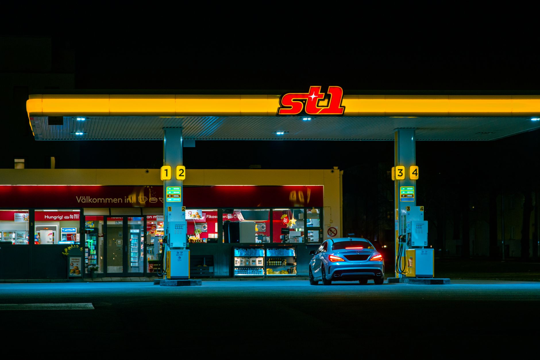 A car refuels at an illuminated petrol station