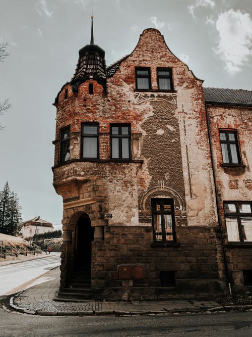 Free Vintage brick building with unique architectural details and rustic charm on a quiet street. Stock Photo