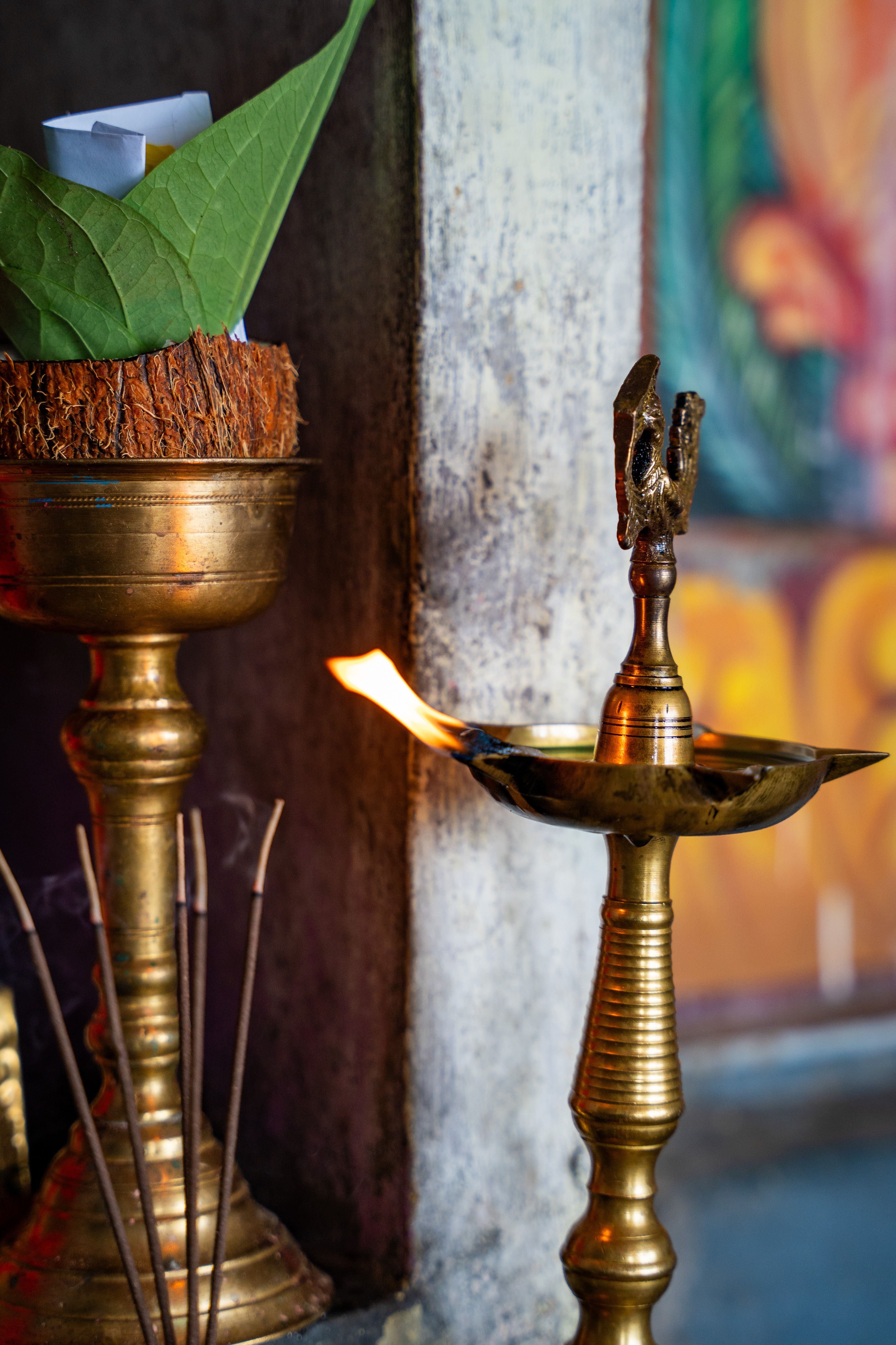 Brass oil lamp with a traditional setup, featuring a coconut and leaves, in a spiritual setting.