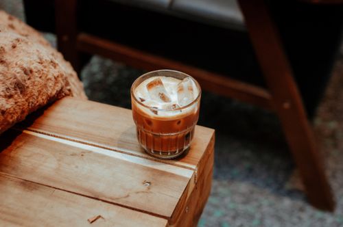Free A glass of iced coffee with milk sits on a rustic wooden table, offering a cozy and inviting feel. Stock Photo