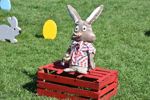 Colorful Easter bunny decoration sitting outside on a sunny day, perfect for spring festivities.