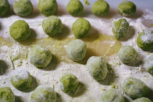 Free Fresh green pasta dough balls resting on a bed of flour, ready for cooking. Stock Photo