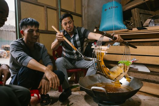 Men preparing fish using traditional methods in an indoor rustic setting.
