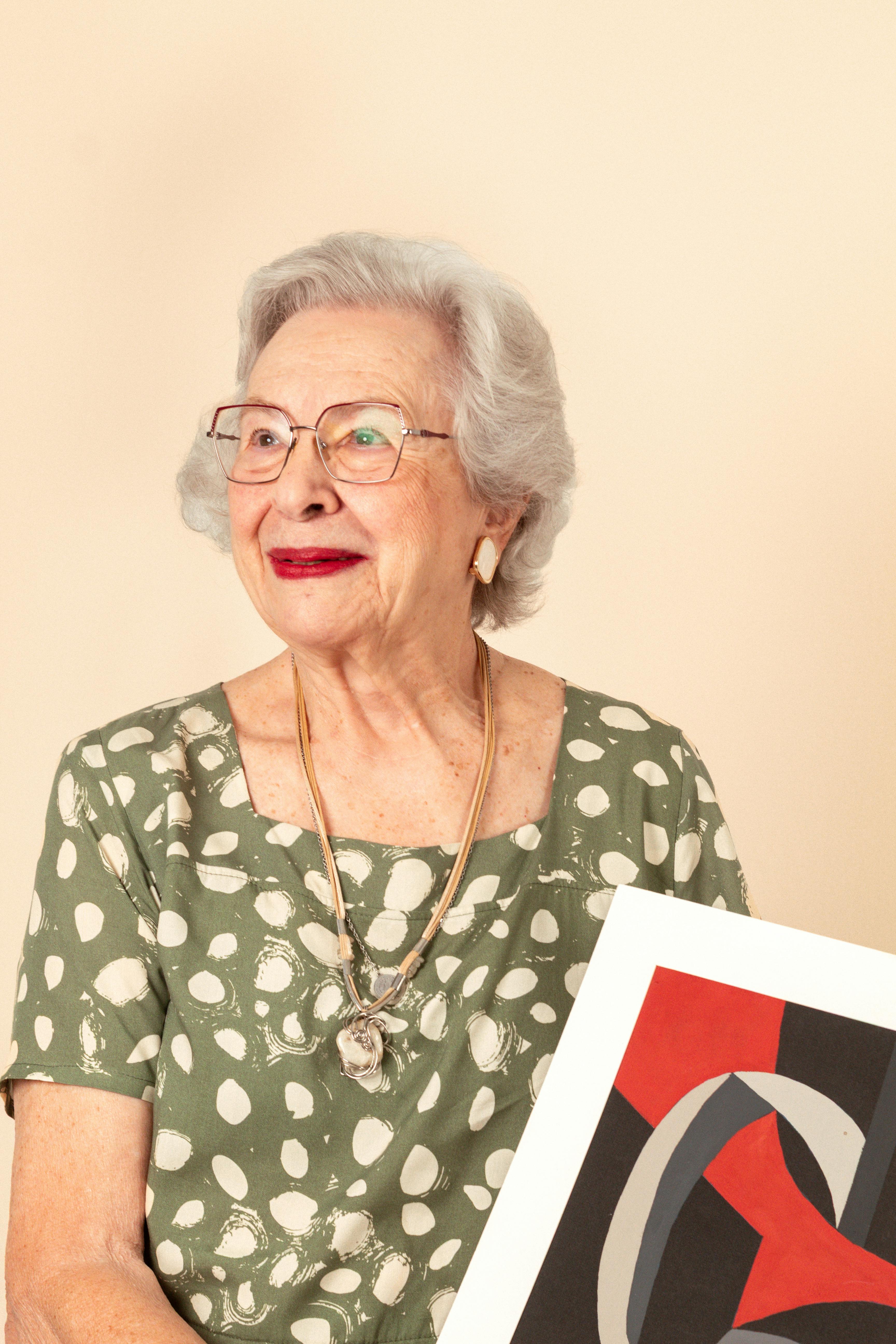 Senior adult woman holding abstract art, exuding elegance and creativity.
