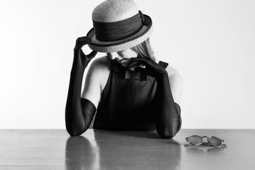 Monochrome portrait of a stylish woman with a hat and gloves, evoking classic vintage elegance.