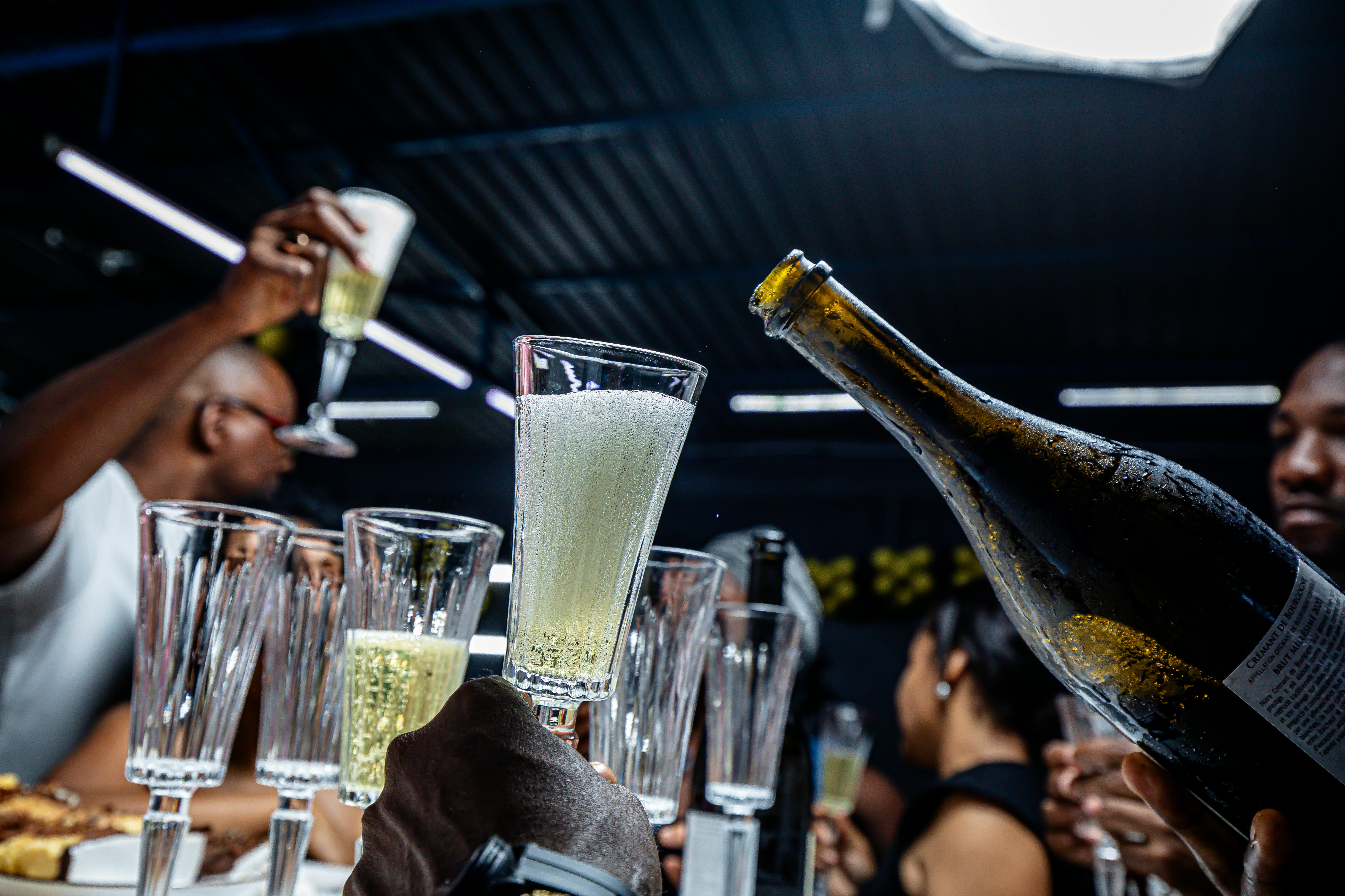 Une fête animée à Luanda, où les gens trinquent avec des coupes de champagne à l'intérieur.
