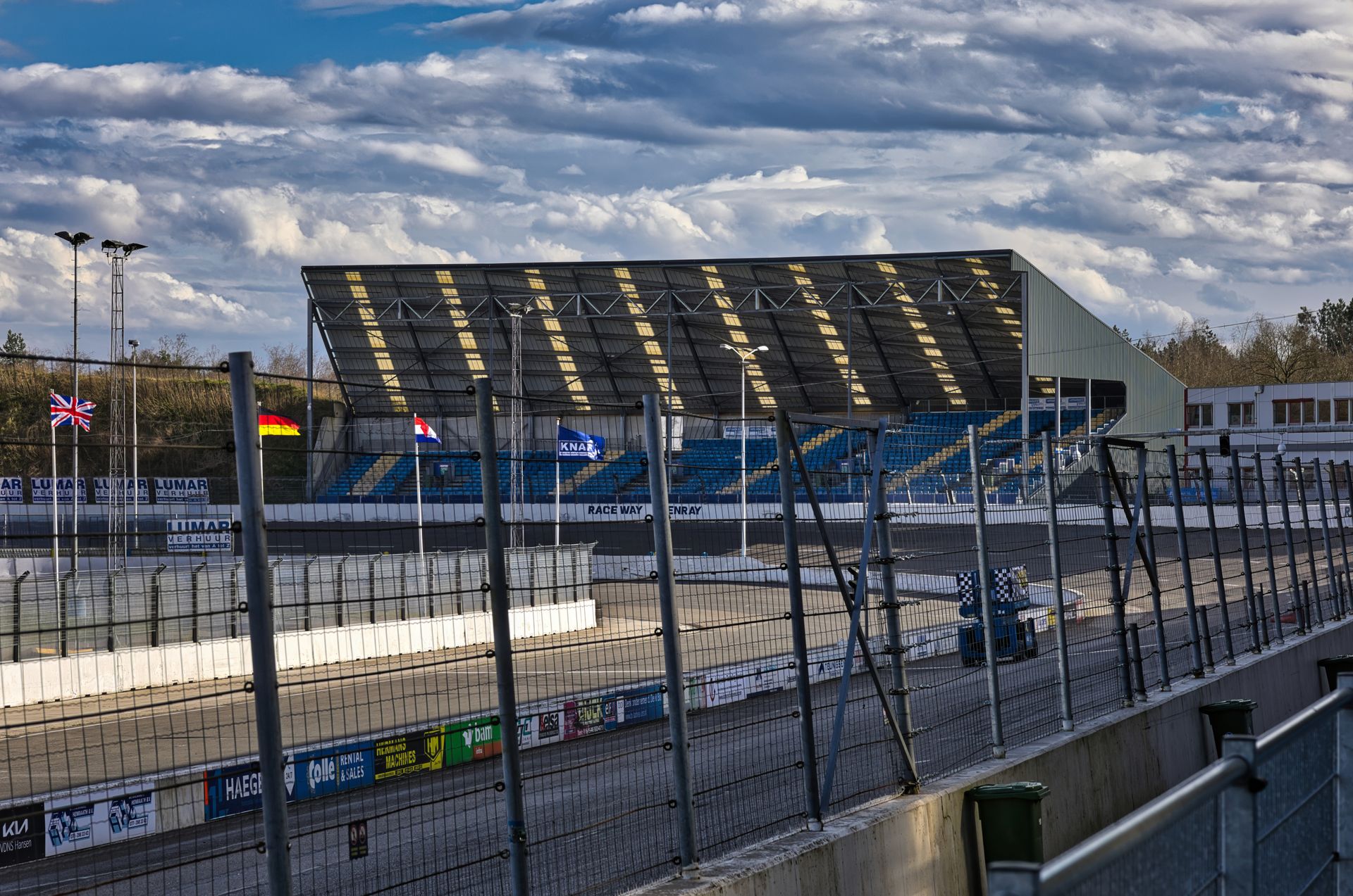 An empty racetrack pit lane at dawn under an overcast sky.
