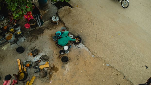 Street vendor in Abuja preparing food outdoors from above, showcasing local culture.