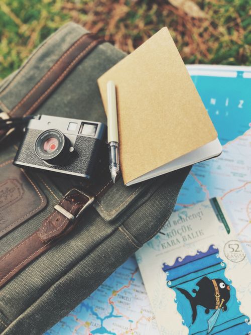 Free A vintage camera and notebook rest atop a travel bag and map, evoking adventure. Stock Photo