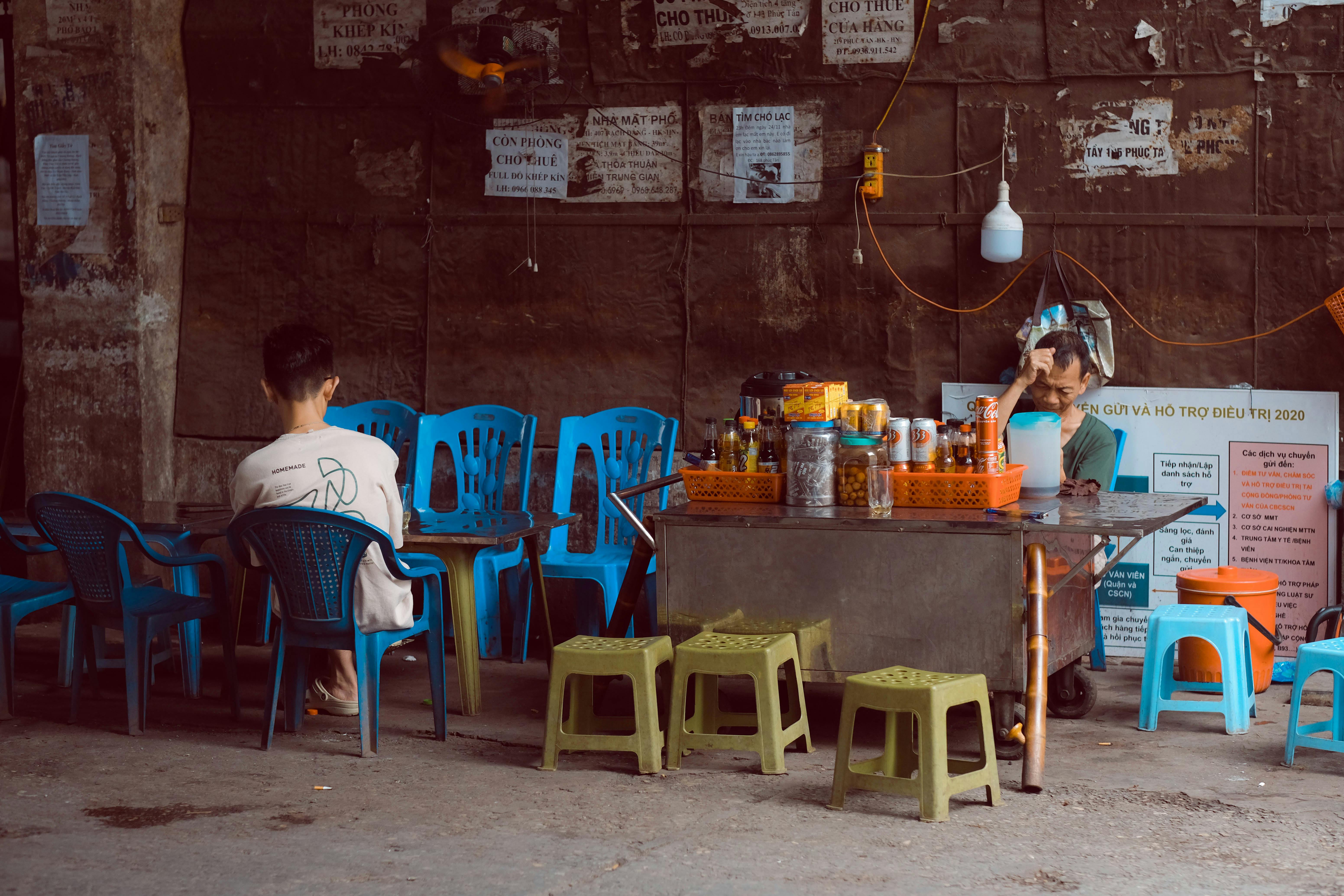 Casual street cafe in Hanoi with blue chairs and rustic setting.