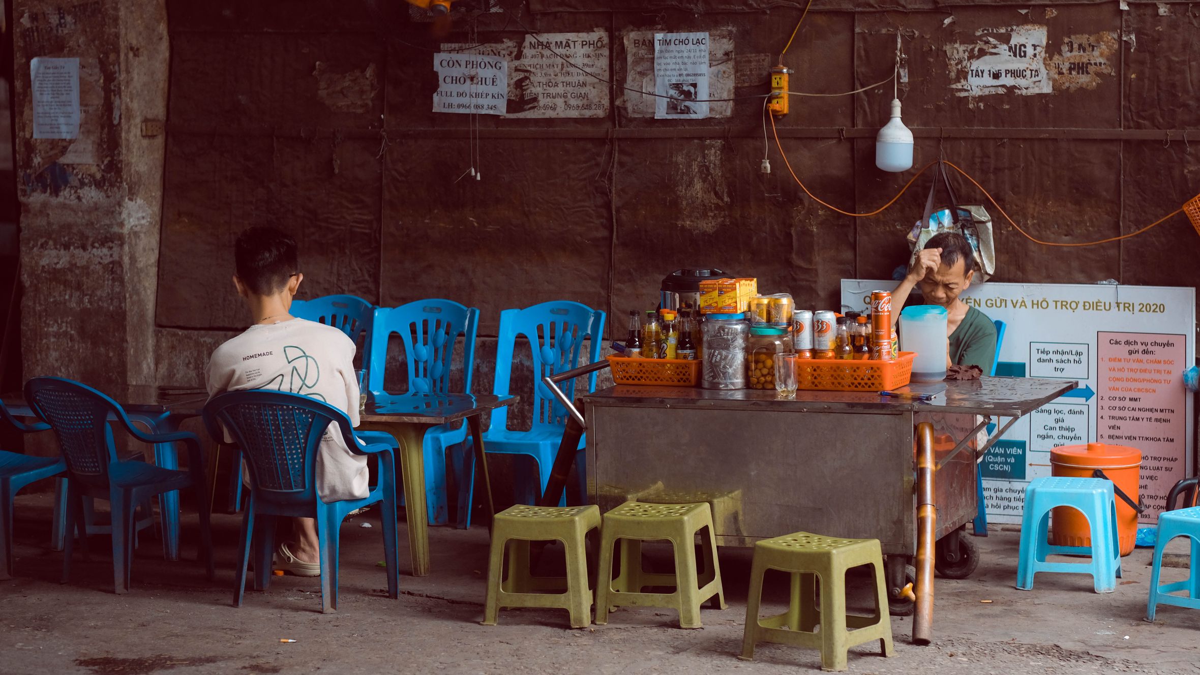 Casual street cafe in Hanoi with blue chairs and rustic setting.