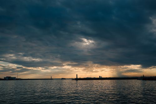 Free Serene sunset at a harbor with dramatic clouds and calm waters, perfect for travel themes. Stock Photo