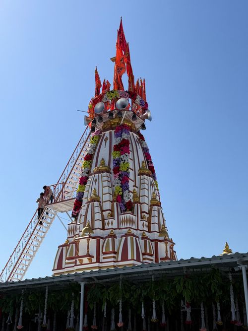 Free Decorative temple festival tower with colorful flowers and flags against a clear blue sky. Stock Photo