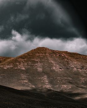 A stunning view of dark clouds looming over a rugged mountain peak, capturing the essence of stormy weather and natural beauty.