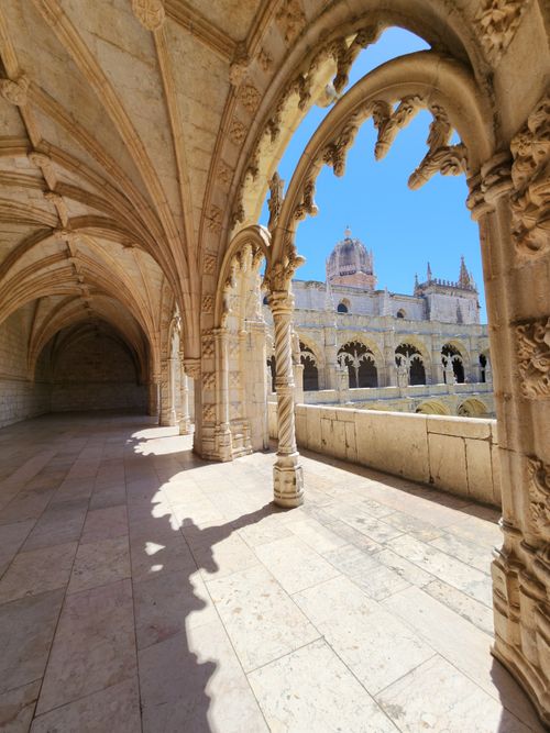 Free Beautiful Gothic architecture in Jerónimos Monastery, Lisbon with ornate archways and blue sky. Stock Photo