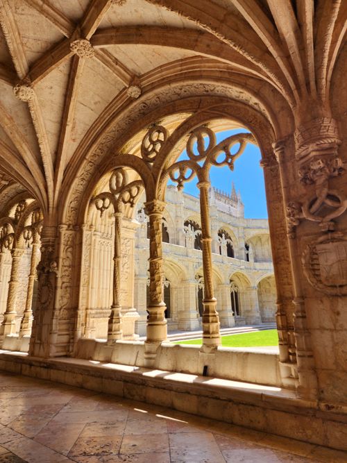 Free Intricate Gothic arches in a historic cloister bathed in sunlight, showcasing ornate stonework. Stock Photo