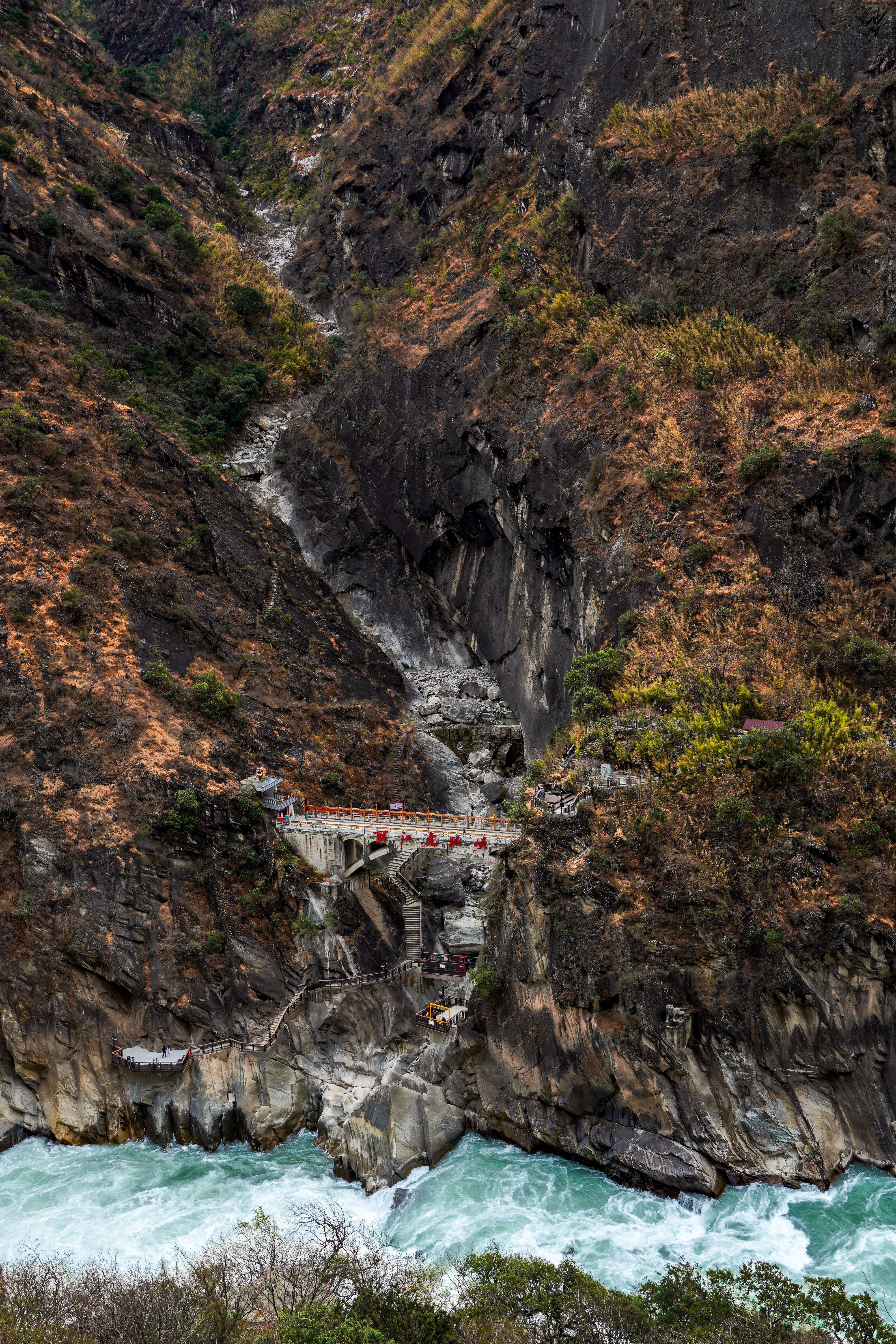 A breathtaking view of Tiger Leaping Gorge in Lijiang, Yunnan, showcasing dramatic cliffs and a raging river.