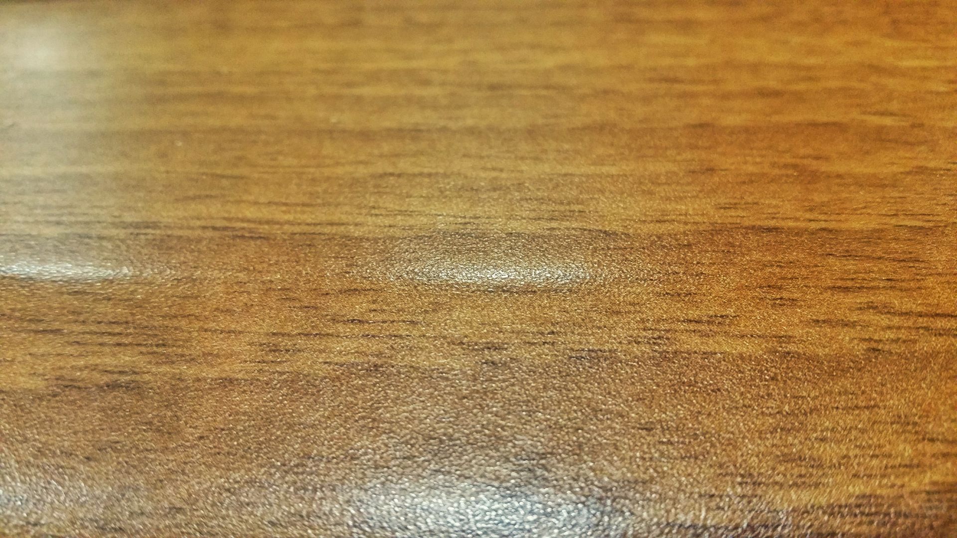 Detailed close-up of a textured hardwood surface, showcasing natural wooden grains and warm earthy tones.