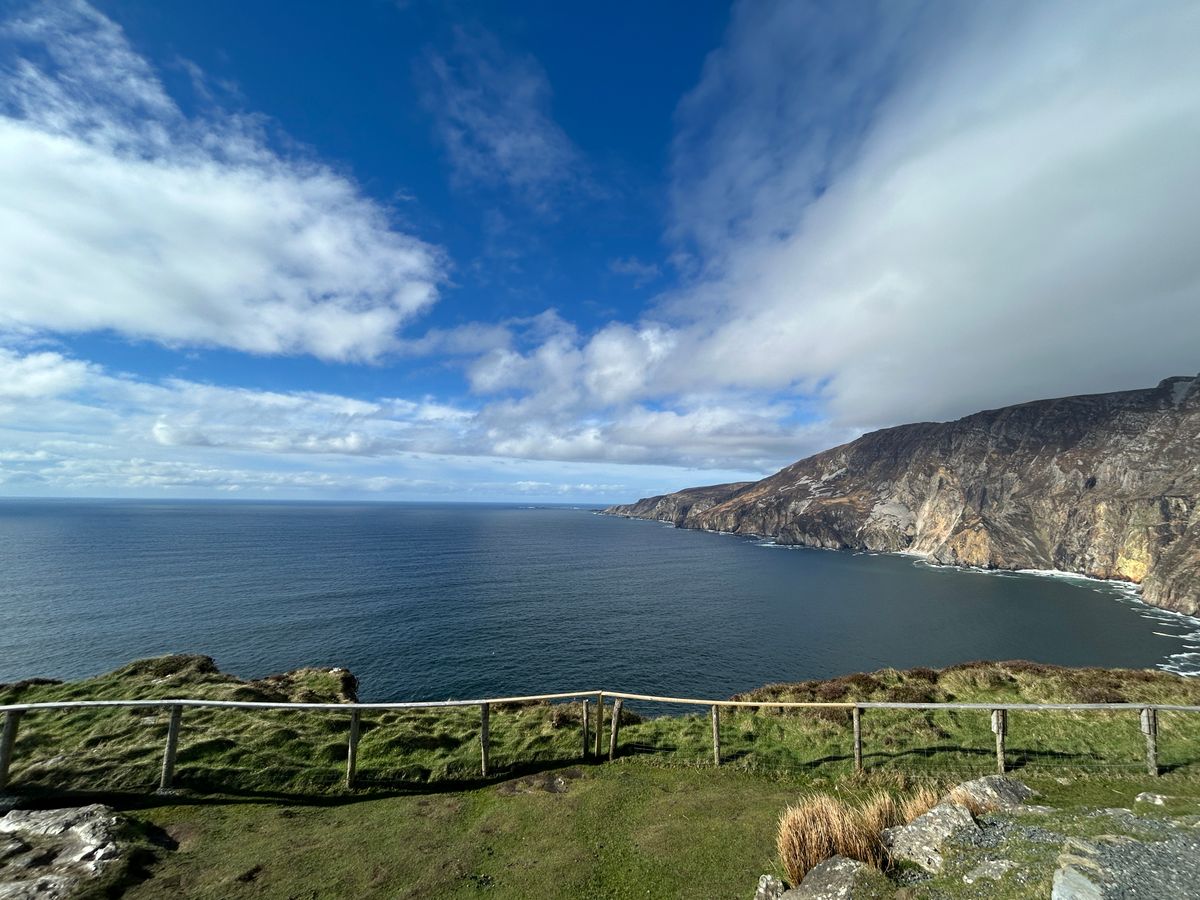 A stunning view of the Slieve League Cliffs meeting the Atlantic Ocean under a bright sky in Ireland.