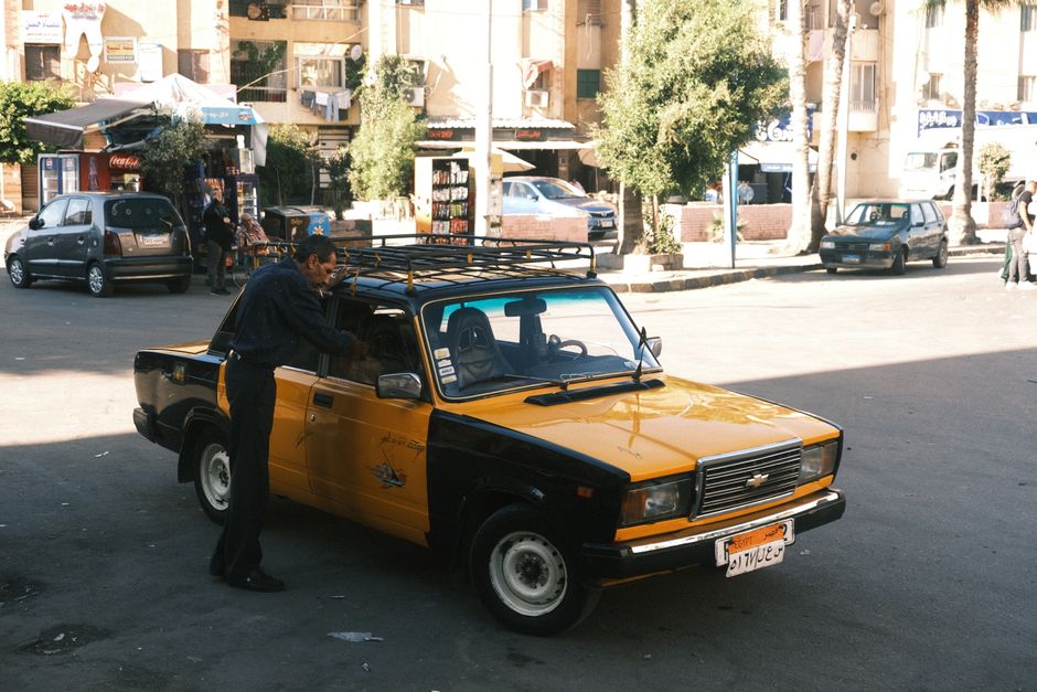 A tourist carefully inspecting and photographing a rental car in Egypt before pick-up, highlighting the importance of pre-rental checks.